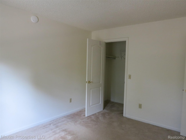 35707 Hunter Ave Unit 8, Westland, MI 48185 - unfurnished bedroom featuring carpet flooring, a spacious closet, a textured ceiling, and a closet