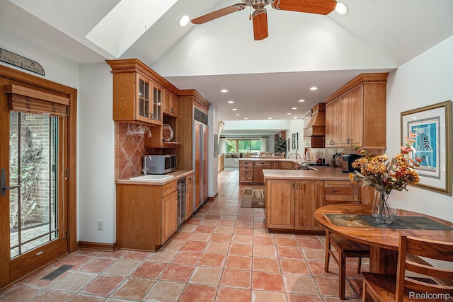 9095 S Saginaw Rd Unit 10, Grand Blanc, MI 48439 - kitchen featuring a peninsula, lofted ceiling, custom exhaust hood, decorative backsplash, and brown cabinets