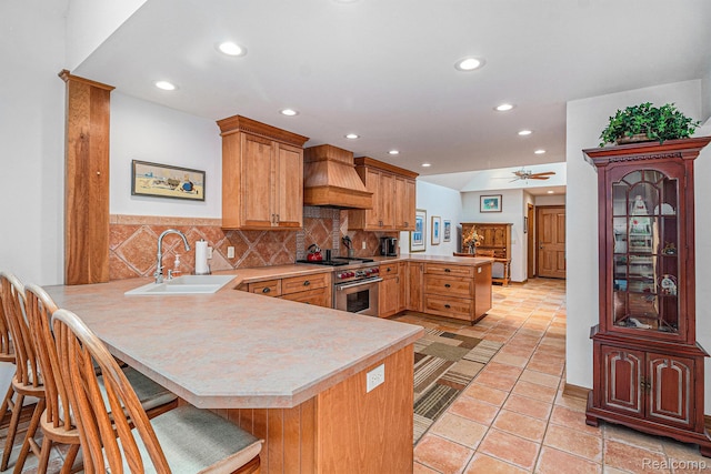 9095 S Saginaw Rd Unit 10, Grand Blanc, MI 48439 - kitchen featuring a peninsula, a sink, custom exhaust hood, high end range, and light countertops