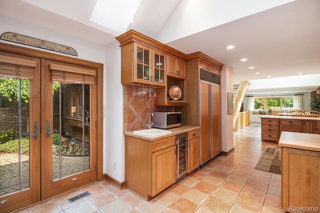 9095 S Saginaw Rd Unit 10, Grand Blanc, MI 48439 - kitchen with beverage cooler, paneled built in fridge, backsplash, glass insert cabinets, and stainless steel microwave