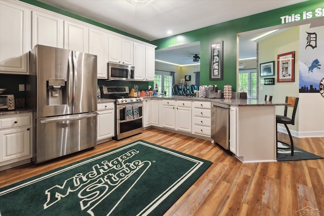 3283 Foxfire Dr, Milford, MI 48380 - kitchen featuring appliances with stainless steel finishes, white cabinets, light wood-type flooring, recessed lighting, and a peninsula