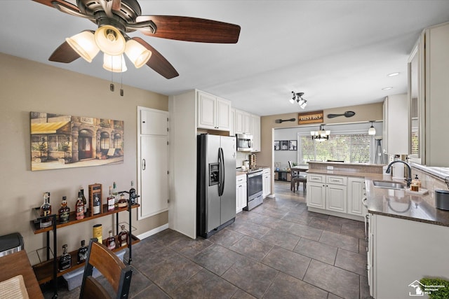 4851 Consear Rd, Ottawa Lake, MI 49267 - kitchen with stainless steel appliances, a sink, a peninsula, a chandelier, and white cabinetry