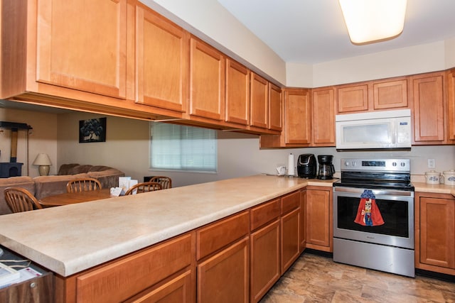 4164 W Centre Ave Unit 103, Portage, MI 49024 - kitchen with stainless steel electric stove, white microwave, light countertops, a peninsula, and brown cabinets