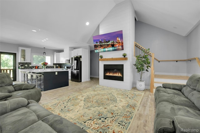 44200 Judd Rd, Belleville, MI 48111 - living room featuring lofted ceiling, a large fireplace, light wood-style flooring, recessed lighting, and baseboards