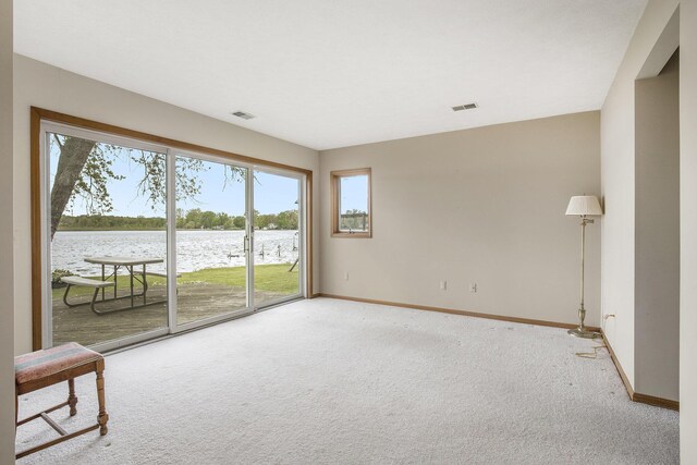 8928 Ellis St SE, Alto, MI 49302 - empty room featuring a water view, light colored carpet, baseboards, and plenty of natural light