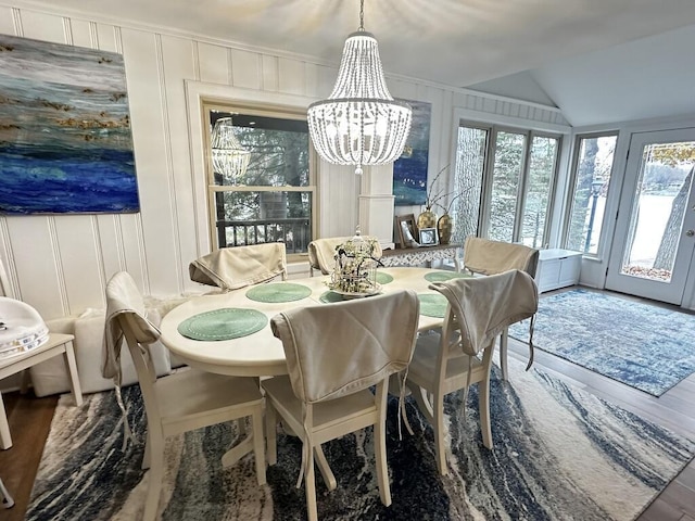 456 E Gull Lake Dr, Augusta, MI 49012 - dining room with healthy amount of natural light, a chandelier, vaulted ceiling, a decorative wall, and wood finished floors
