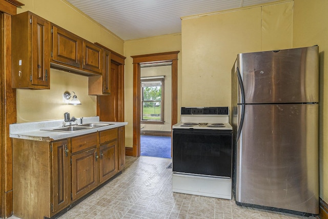 393 Merrill Ave, Muskegon, MI 49441 - kitchen with freestanding refrigerator, white range with electric cooktop, a sink, light countertops, and brown cabinetry