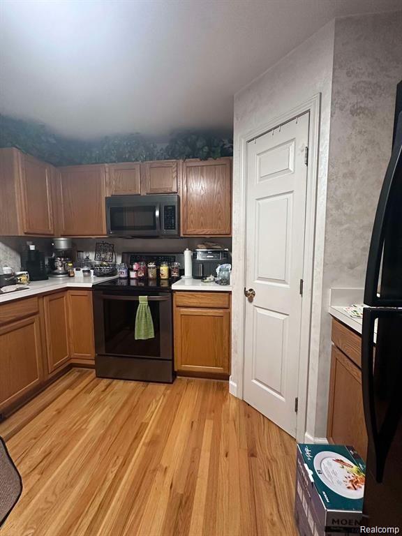 5400 Bright Creek Ct, Flint, MI 48532 - kitchen with black appliances, light wood-type flooring, brown cabinetry, and light countertops