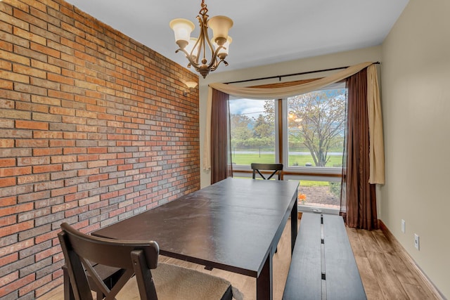 11245 Antcliff Rd, Brooklyn, MI 49230 - dining room featuring brick wall, a chandelier, light wood-type flooring, and baseboards
