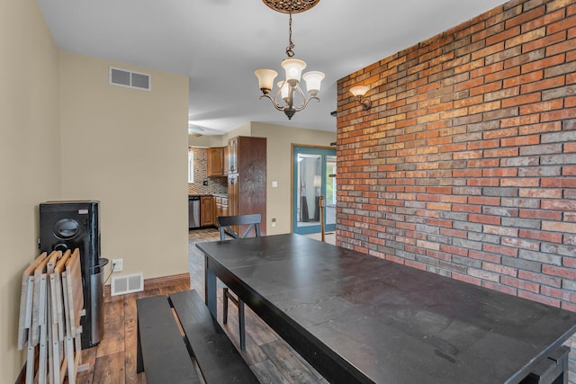 11245 Antcliff Rd, Brooklyn, MI 49230 - dining room featuring brick wall, a chandelier, wood finished floors, and baseboards