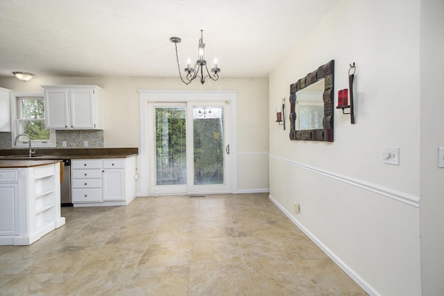 7289 Eagle Ter, Michigan, MI 49071 - kitchen featuring dark countertops, a sink, a chandelier, white cabinetry, and decorative backsplash