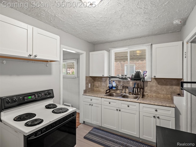 15058 Vaughan St, Detroit, MI 48223 - kitchen with range with electric stovetop, a sink, white cabinetry, decorative backsplash, and light countertops