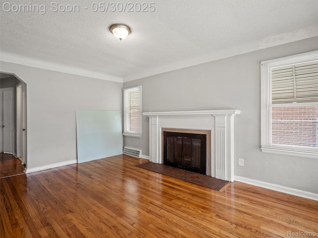 15058 Vaughan St, Detroit, MI 48223 - unfurnished living room featuring a textured ceiling, a glass covered fireplace, wood finished floors, arched walkways, and baseboards