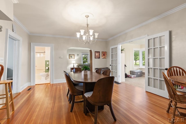 2803 Spielman Rd, Adrian, MI 49221 - dining space featuring arched walkways, light wood finished floors, french doors, a chandelier, and ornamental molding