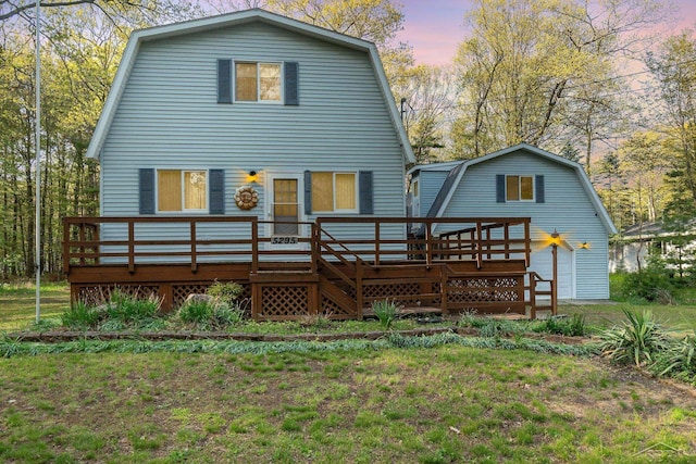 5295 E 14th St, Au Gres, MI 48703 - back of property at dusk with a gambrel roof and a wooden deck