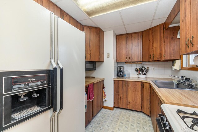 5295 E 14th St, Au Gres, MI 48703 - kitchen featuring white refrigerator with ice dispenser, a sink, brown cabinetry, light countertops, and a drop ceiling