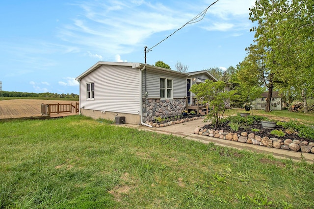 1981 E Wolf Rd, Hart, MI 49420 - view of home's exterior featuring a wooden deck, a lawn, and central air condition unit