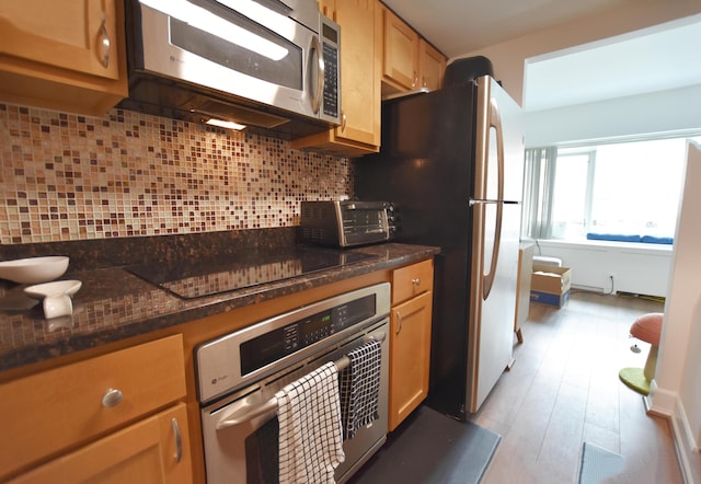 555 E William St Unit 5C, Ann Arbor, MI 48104 - kitchen with appliances with stainless steel finishes, tasteful backsplash, wood finished floors, and dark stone countertops