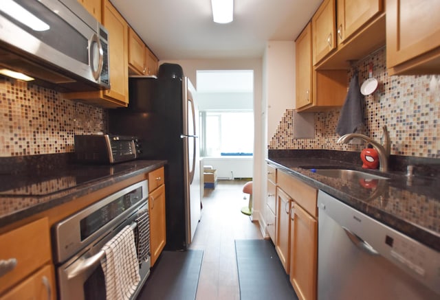 555 E William St Unit 5C, Ann Arbor, MI 48104 - kitchen with appliances with stainless steel finishes, backsplash, a sink, and dark stone counters