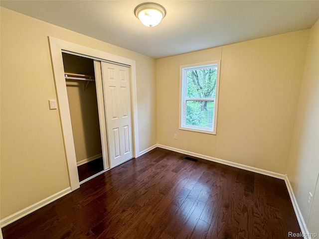 8909 E Country Ln, Lennon, MI 48449 - unfurnished bedroom with dark wood-type flooring, baseboards, and a closet