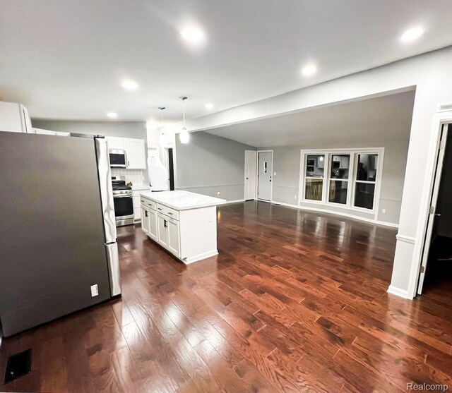 8909 E Country Ln, Lennon, MI 48449 - kitchen featuring stainless steel appliances, white cabinets, open floor plan, dark wood-style floors, and pendant lighting
