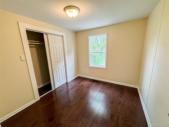 8909 E Country Ln, Lennon, MI 48449 - unfurnished bedroom featuring dark wood finished floors, baseboards, and a closet