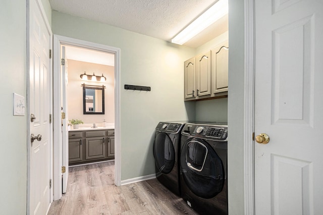 2441 Butterfly Ln, Berrien Springs, MI 49103 - laundry room with cabinet space, washer and dryer, light wood-type flooring, a textured ceiling, and baseboards