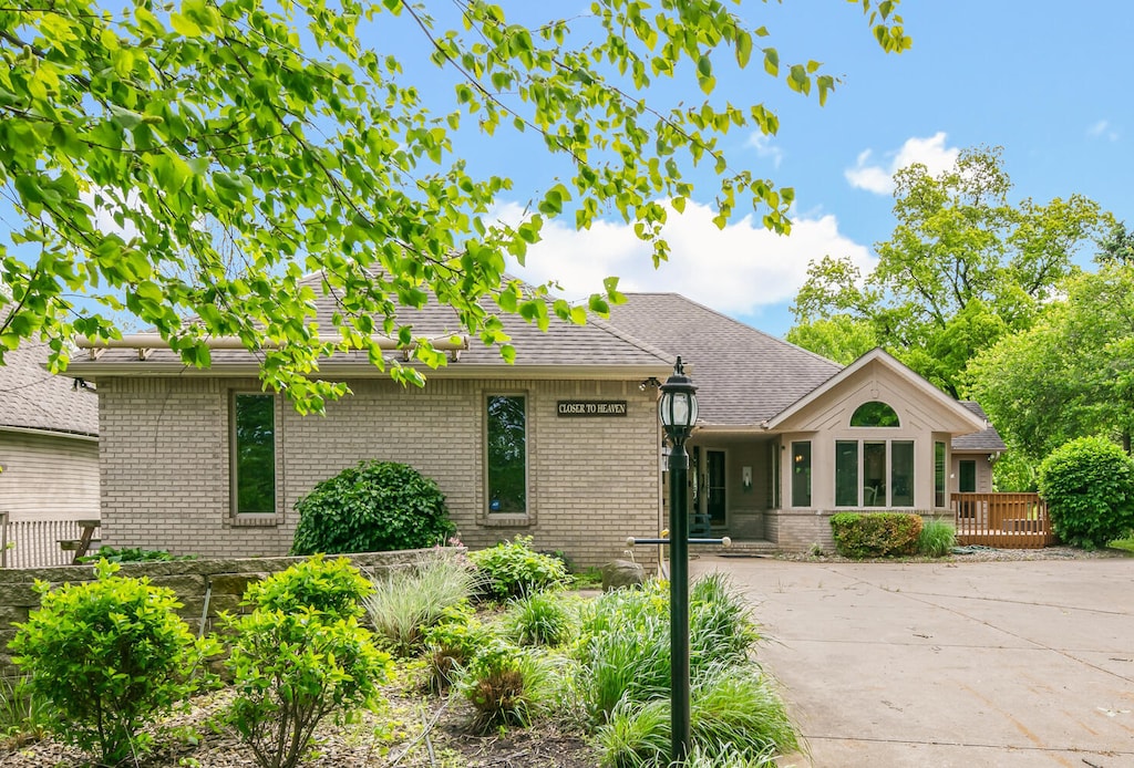 63093 Birch Rd, Vandalia, MI 49095 - view of front of property featuring brick siding, a wooden deck, driveway, and roof with shingles