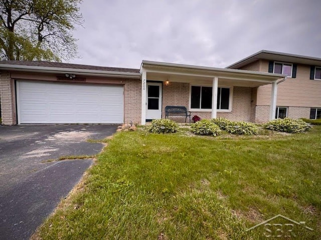 7200 Danny Dr, Saginaw, MI 48609 - split level home featuring brick siding, asphalt driveway, an attached garage, a front yard, and covered porch