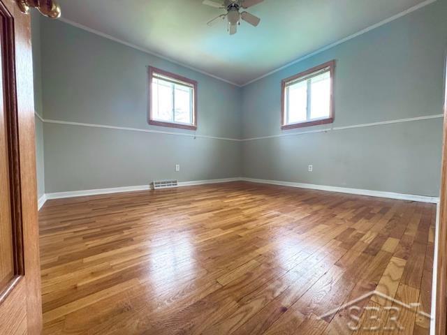 7200 Danny Dr, Saginaw, MI 48609 - spare room featuring crown molding, healthy amount of natural light, a ceiling fan, wood finished floors, and baseboards