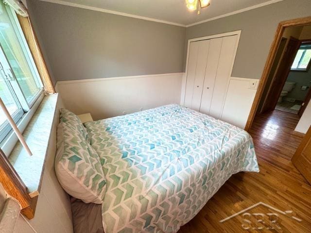 7200 Danny Dr, Saginaw, MI 48609 - bedroom with wood finished floors, crown molding, wainscoting, and a closet