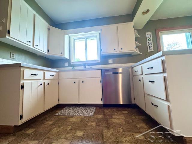 7200 Danny Dr, Saginaw, MI 48609 - kitchen with stainless steel dishwasher, stone finish floors, white cabinets, and light countertops