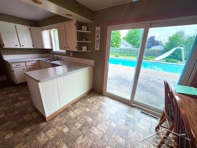 7200 Danny Dr, Saginaw, MI 48609 - kitchen with light countertops, white cabinets, a peninsula, and stone finish flooring