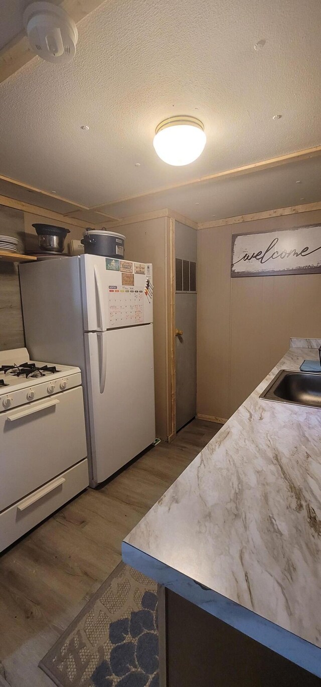 11384 N Irons Rd, Irons, MI 49644 - kitchen with white appliances, wood finished floors, a sink, and a textured ceiling