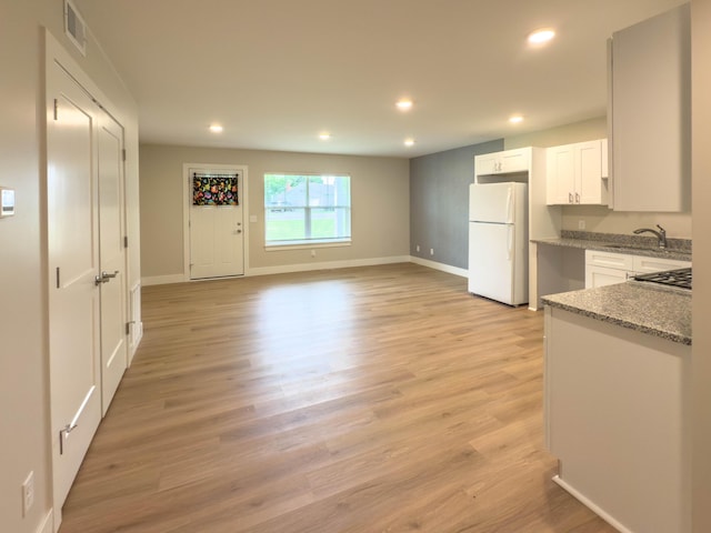 12773 Felch St, Holland, MI 49424 - kitchen with freestanding refrigerator, recessed lighting, light stone counters, white cabinets, and light wood-style floors