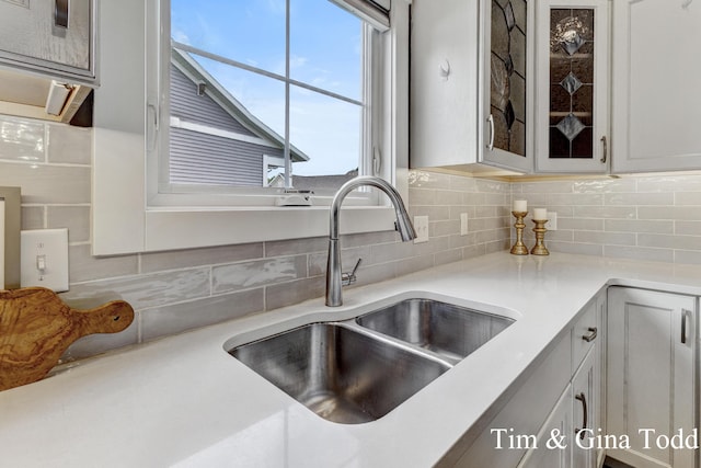 903 S Center Park Dr SW Unit 14, Byron Center, MI 49315 - kitchen featuring a sink, glass insert cabinets, decorative backsplash, and light countertops