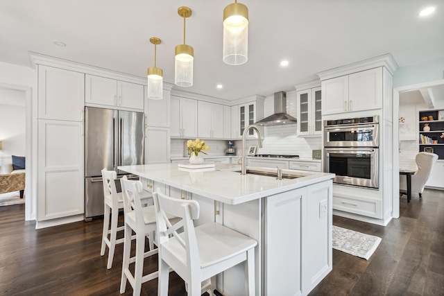 4396 Laurel Dr, Saint Joseph, MI 49085 - kitchen with stainless steel appliances, wall chimney exhaust hood, dark wood-type flooring, a center island with sink, and white cabinets