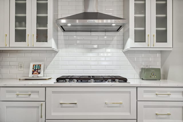 4396 Laurel Dr, Saint Joseph, MI 49085 - kitchen featuring wall chimney exhaust hood, stainless steel gas stovetop, backsplash, and glass insert cabinets