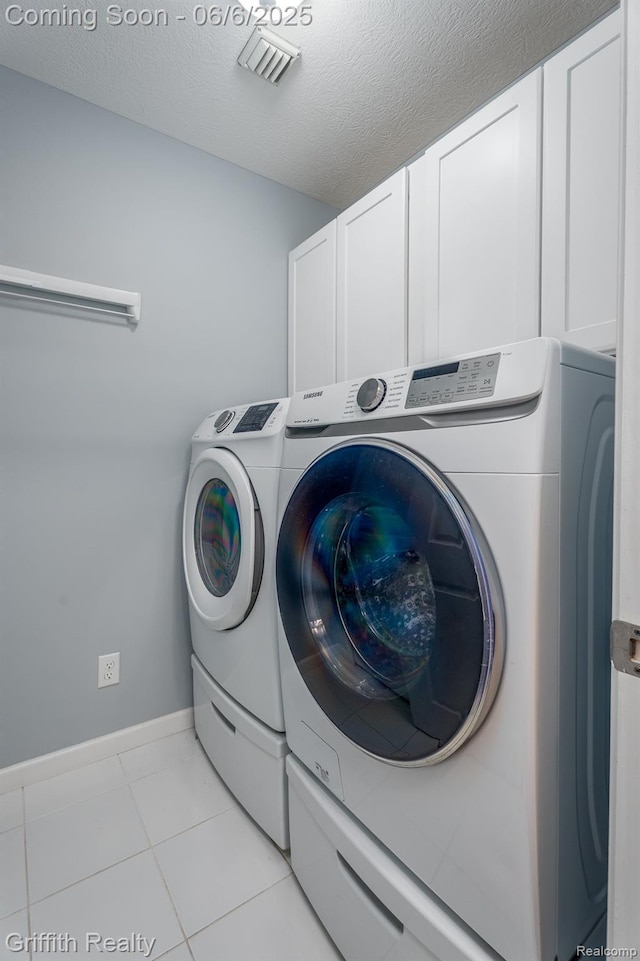 2870 Grand Marais Dr, Howell, MI 48843 - laundry room featuring washing machine and dryer, cabinet space, baseboards, light tile patterned floors, and a textured ceiling