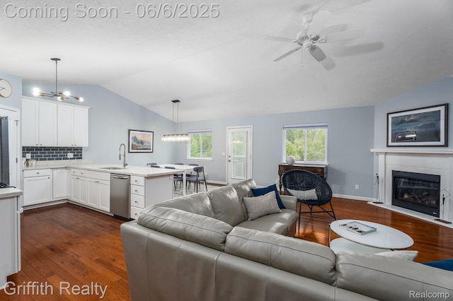 2870 Grand Marais Dr, Howell, MI 48843 - living area featuring lofted ceiling, dark wood-style flooring, a ceiling fan, a fireplace with flush hearth, and a chandelier