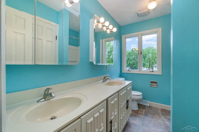 5211 S Gatesboro Dr, Saginaw, MI 48603 - full bathroom with a textured ceiling, double vanity, toilet, baseboards, and stone finish floors