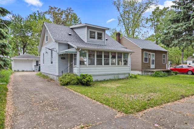 1141 E Madge Ave, Hazel Park, MI 48030 - view of front of house featuring an outbuilding, a front yard, roof with shingles, a chimney, and a detached garage