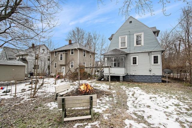 905 Lane Ave, Kalamazoo, MI 49001 - snow covered rear of property featuring a sunroom, a gambrel roof, and an outdoor fire pit