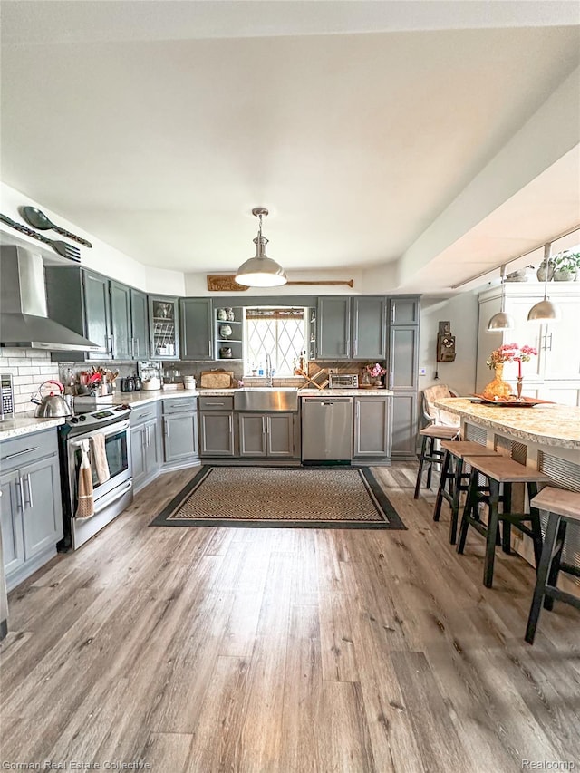2109 S Lakeshore Rd, Harbor Beach, MI 48441 - kitchen with stainless steel appliances, wall chimney exhaust hood, light countertops, and wood finished floors