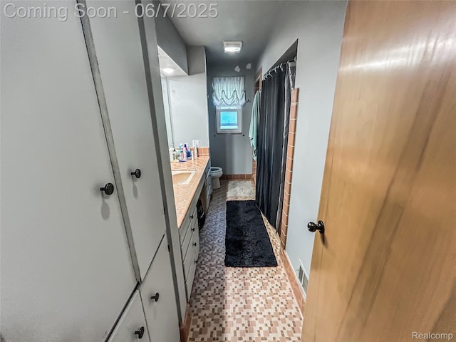 2211 N Sycamore Dr, Burton, MI 48509 - full bath with toilet, double vanity, a shower with shower curtain, and baseboards