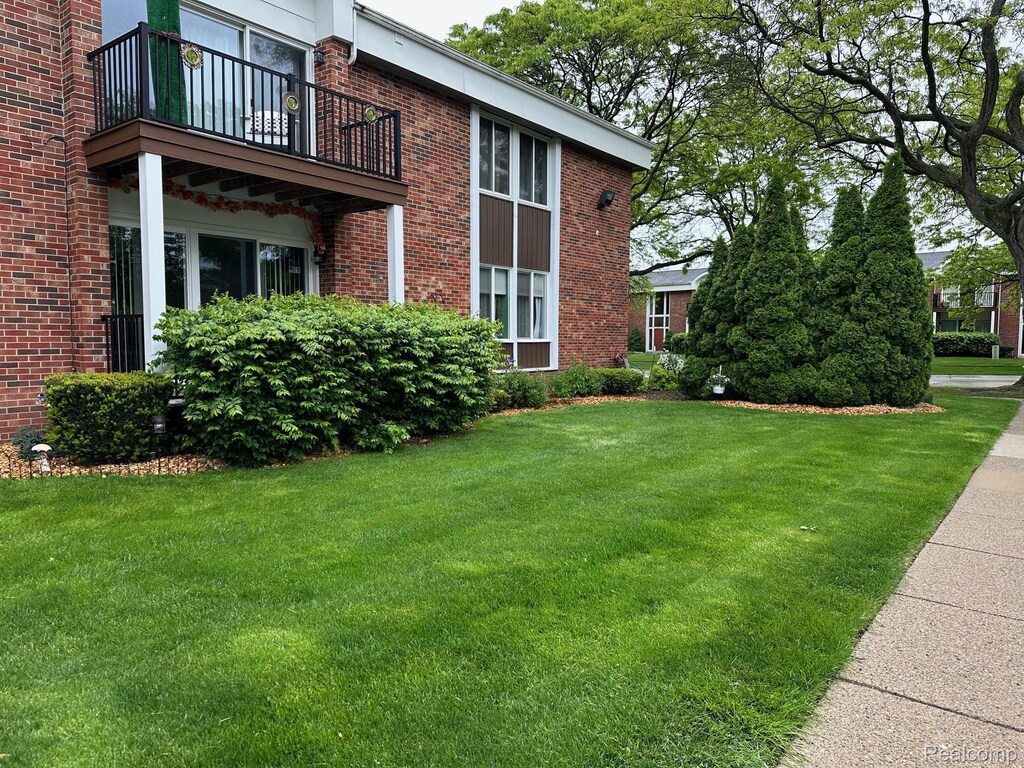 29446 Bobrich St Unit 63, Southgate, MI 48152 - view of property exterior with a balcony, brick siding, and a lawn