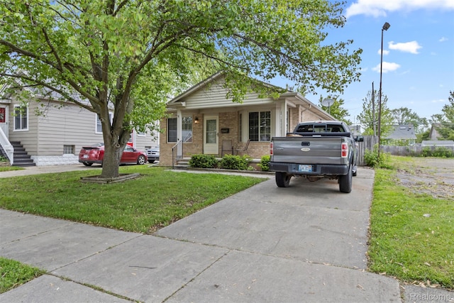 23847 Deziel St, Grosse Pointe, MI 48082 - view of front of home featuring a front yard, brick siding, a porch, and driveway
