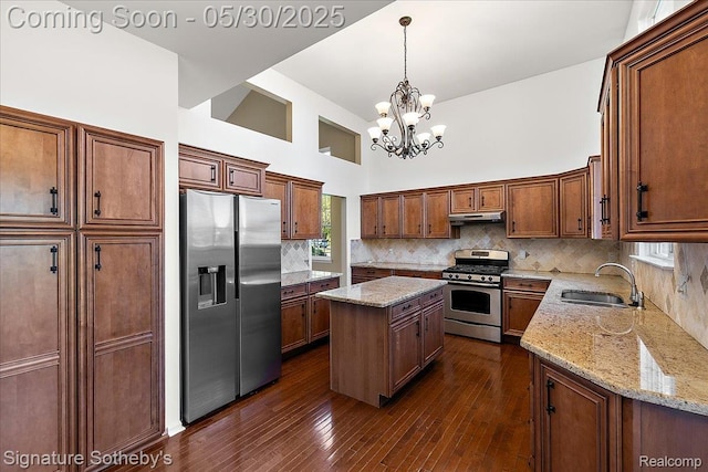 31190 Kingsley Ct, Novi, MI 48377 - kitchen with appliances with stainless steel finishes, under cabinet range hood, a kitchen island, a chandelier, and a towering ceiling