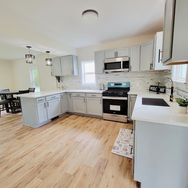 2109 Schippers Ln, Kalamazoo, MI 49048 - kitchen featuring appliances with stainless steel finishes, gray cabinets, a sink, light wood-style flooring, and a peninsula