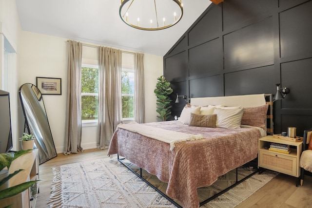 1819 Gloryfield Dr SW, Byron Center, MI 49315 - bedroom featuring light wood-style floors, lofted ceiling, a chandelier, baseboards, and a decorative wall